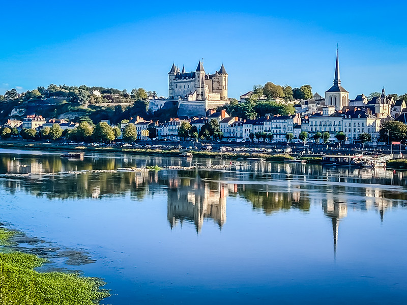 Foto van het kasteel van Saumur met de Loire op de voorgrond en de klokkentoren van de Saint-Pierre kerk